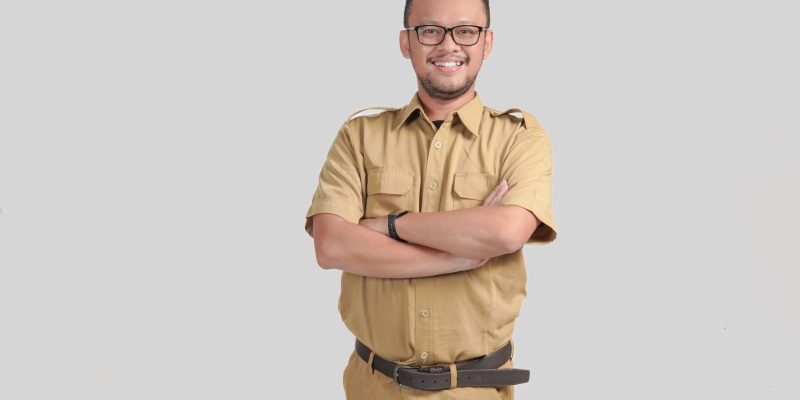 Confident government worker man wearing khaki uniform smiling and standing with his arms crossed. PNS civil servant concept.